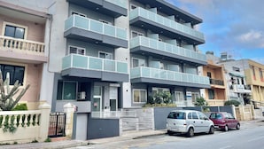 Un immeuble résidentiel à plusieurs étages, doté de balcons, abritant un cabinet dentaire, et avec une voiture garée devant.