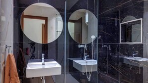 Une salle de bain moderne avec deux lavabos, une douche et trois grands miroirs.