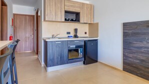 A compact kitchen with a built-in oven, a microwave, and a refrigerator. - Blue 6: Studio Apartment in St. Julian's (Swieqi)