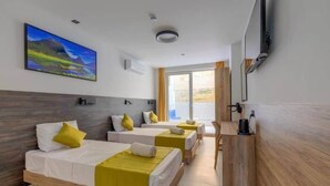 A hotel room with three beds, a TV, and a window with curtains. - Blue 7: Studio Apartment in St. Julian's (Swieqi)