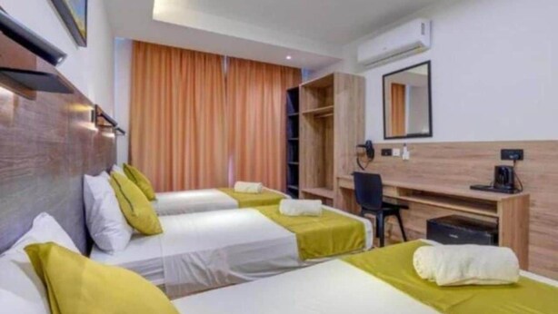 A hotel room with two beds, a desk, a chair, and a wardrobe. - Blue 7: Studio Apartment in St. Julian's (Swieqi)