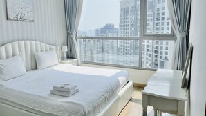 Quarto de hotel moderno com uma cama grande, uma mesa de cabeceira e vista para edifícios altos.