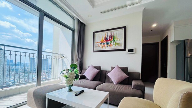 Uma sala de estar moderna com um sofá, uma mesa de centro e vista para a cidade através de grandes janelas.