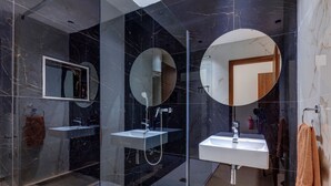 Een moderne badkamer met twee wastafels, een douche met glazen wanden en een grote spiegel.