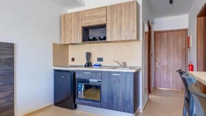Een compacte keuken met houten kastjes, een inbouwoven en een klein spoelbakje.