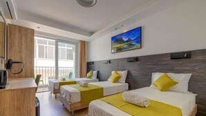 Een hotelkamer met twee bedden, een bureau en een groot raam.