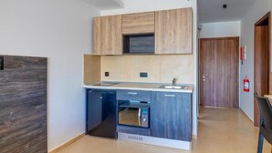 A compact kitchen with wooden cabinets, a built-in microwave, and a dishwasher. - Yellow 13: Two-Bedroom Apartment in St. Julian's (Swieqi)