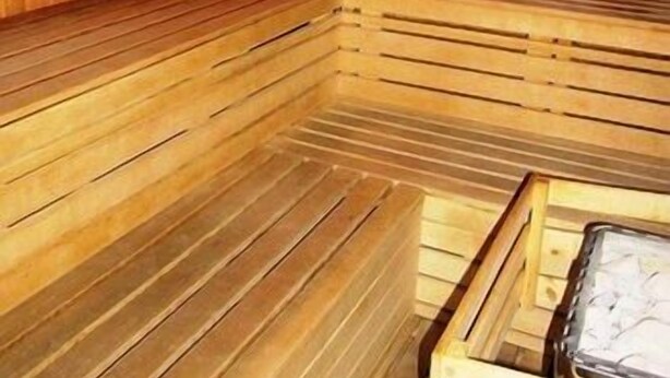 Una sauna con panche di legno e una panca con un asciugamano.
