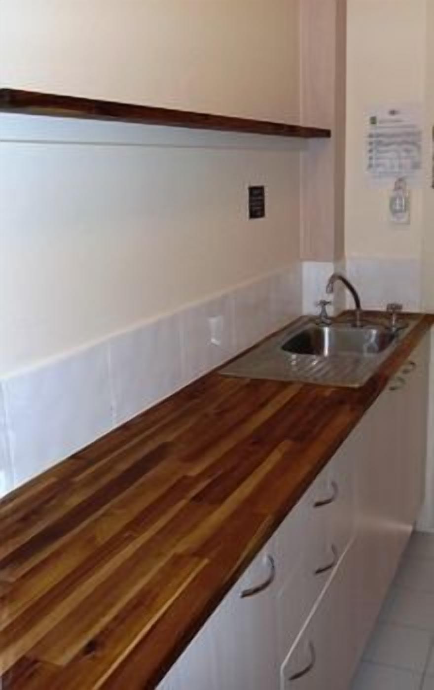 A kitchen with a wooden countertop, a sink, and a cabinet with drawers.