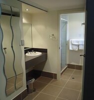 Un baño con lavamanos, espejo y ducha.