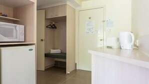 Una cucina compatta con forno a microonde, frigorifero e un piccolo ripiano.
