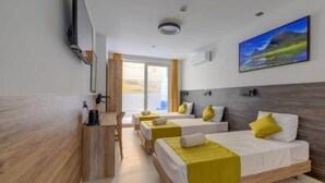 Ein Hotelzimmer mit zwei Betten, einem Schreibtisch und einem Fernseher.