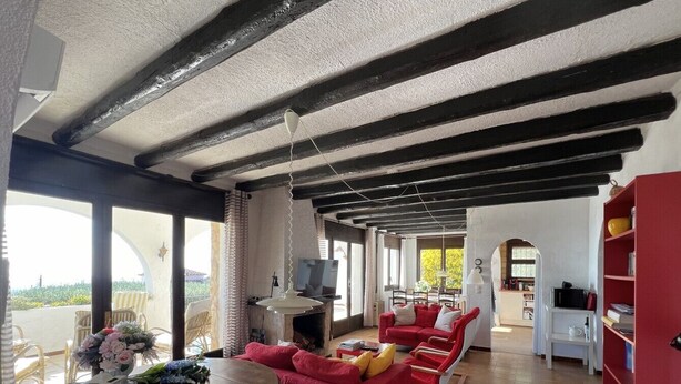 A spacious living room with a fireplace, red sofas, and a dining area with a round table. - Rustic holiday home for 6 people, sea view, 3 bedrooms, air conditioning, Wi-Fi (El Mas Fumats)