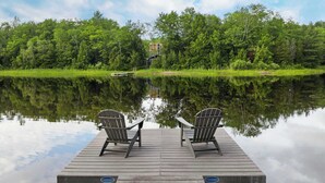 A wooden dock with two chairs facing a calm lake, surrounded by dense green trees. - Lakefront 3-BR Retreat in the Berkshires (Becket)