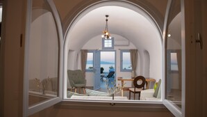 Una habitación con techo abovedado, vista al mar, una mesa de comedor y una silla.