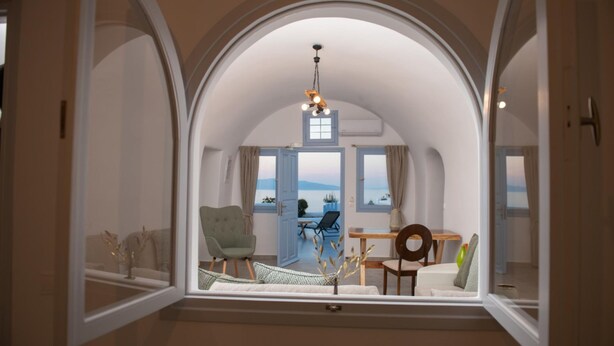 Una habitació amb sostre apuntat, vista al mar, una taula de menjador i una cadira.