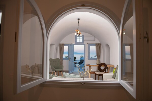 Ein Zimmer mit gewölbter Decke, Meerblick, einem Esstisch und einem Stuhl.
