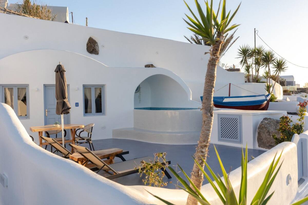 Un edificio blanco con piscina, sillas de descanso y un bote.