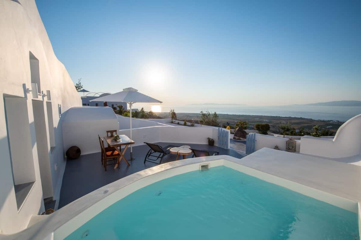 Una piscina en la azotea con vista al mar, arquitectura blanca y mobiliario de exterior.