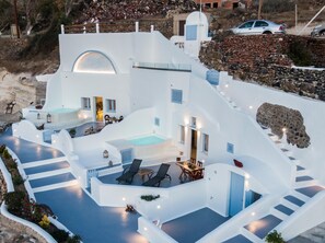 A white building with a pool, outdoor seating, and a staircase.