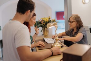 Ein Empfangsschalter mit einer Vase gelber Blumen, einer Schreibtischlampe und Dokumenten auf der Theke.