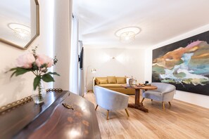Ein modernes Wohnzimmer mit einem Holztisch, zwei Sesseln, einer Couch und einem großen, abstrakten Gemälde an der Wand.