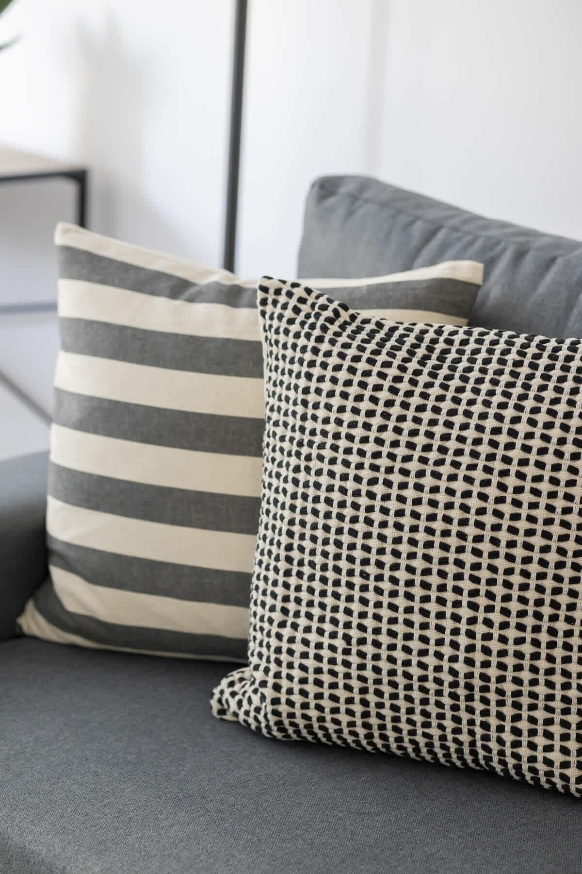 Two pillows with distinct patterns on a grey sofa.