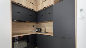 A compact kitchen with a built-in oven, a coffee maker, and a sink.