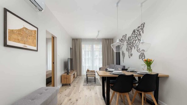 A modern living room with a dining area, a grey bench, a map artwork, and a hanging light fixture.
