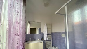 Un bany amb un lavabo, un mirall, dues vàteres i una zona de dutxa.