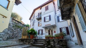 Una estrecha calle con escalones de piedra que conducen a un edificio con varios balcones y macetas con plantas.