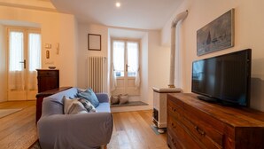 Una sala de estar con sofá, cómoda de madera, televisor y un cuadro en la pared.