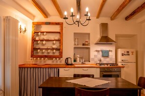Une cuisine avec des poutres en bois, un lustre, une cuisinière et un réfrigérateur.