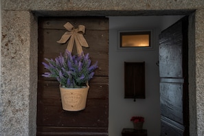 A wooden door with a hanging planter of lavender, a bow, and a sign reading "Flowers & Garden".