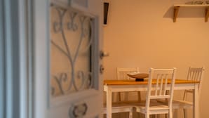 Un coin repas avec une table en bois et des chaises blanches, une porte décorative et une étagère au-dessus de la table.