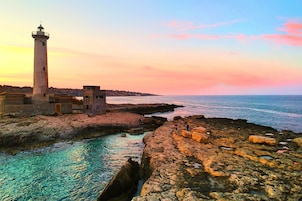 Un paysage côtier avec un phare, une côte rocheuse et une mer calme.