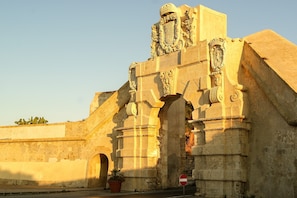 Une structure en pierre d’époque, dotée d’arches et de sculptures détaillées, notamment un blason.