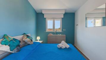 Un dormitorio con cama, cómoda, ventana y vistas al exterior.