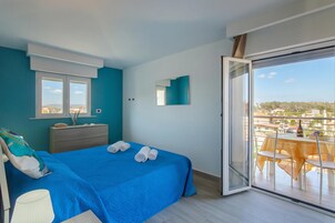 Un dormitorio con cama, cómoda, espejo y balcón con mesa y sillas.
