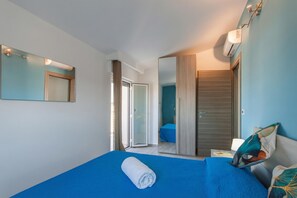 Une chambre d’hôtel comprenant un lit, un miroir, une armoire et une porte coulissante donnant accès à la salle de bain.