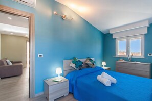 Une chambre à coucher avec un lit, des tables de chevet, une commode, une lampe et une fenêtre.
