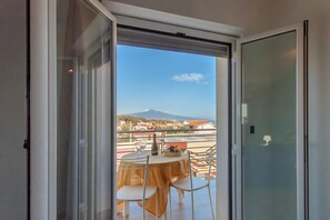 A balcony with a table and chairs, a bottle, and a bowl of fruit. - Casa Golf a 200m From The Sea (Augusta)