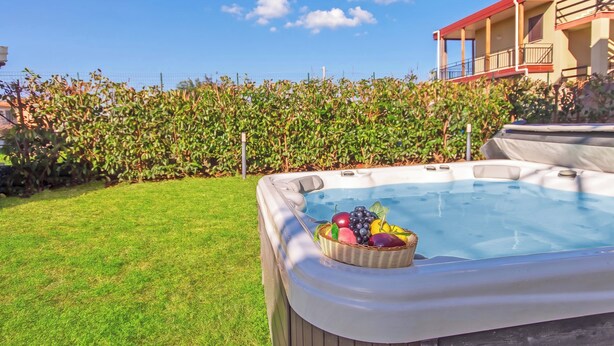 A hot tub with a basket of fruit, surrounded by a well-maintained lawn and a hedge.