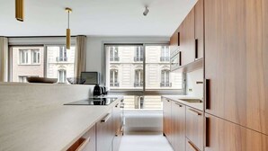 A modern kitchen with wooden cabinets, a large window, and a view of buildings. - A Breathtaking 3-BR/3BA in Trocadéro - Tour Eiffel (Paris)