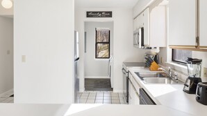 A modern kitchen with white cabinetry, a built-in oven, a sink, and a window above the door. - 2-bedroom, 2-bathroom in the heart of Branson, MO. Walk-in Unit.




 (Branson)