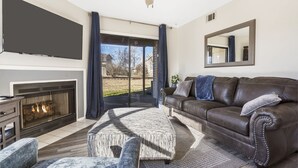 A living room with a fireplace, leather sofa, ottoman, and a large flat-screen TV. - 2-bedroom, 2-bathroom in the heart of Branson, MO. Walk-in Unit.




 (Branson)