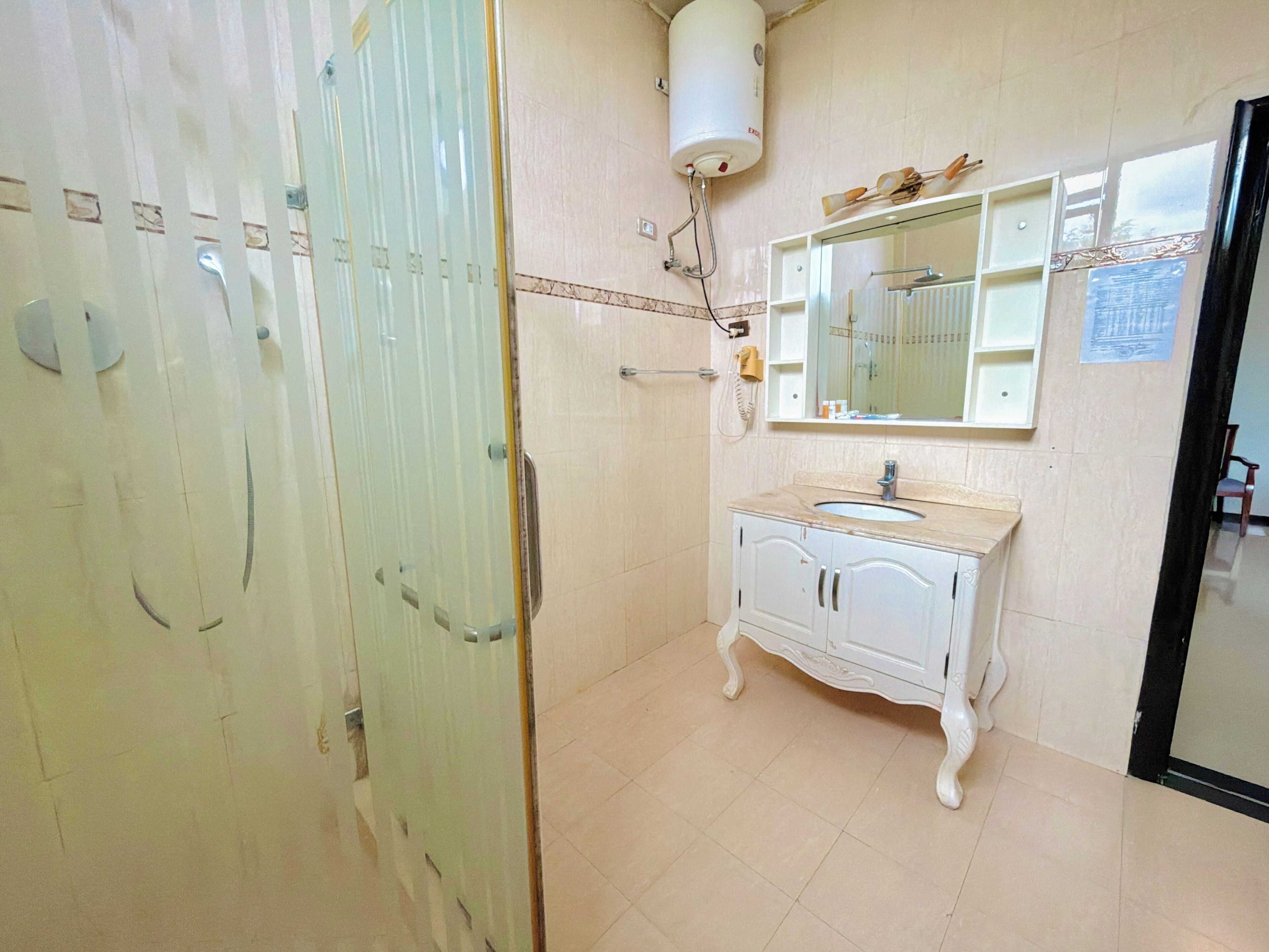 Un baño con tocador blanco, espejo y perchero.
