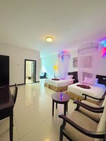 Habitación de hotel con dos camas, un televisor, una pequeña mesa y una silla.