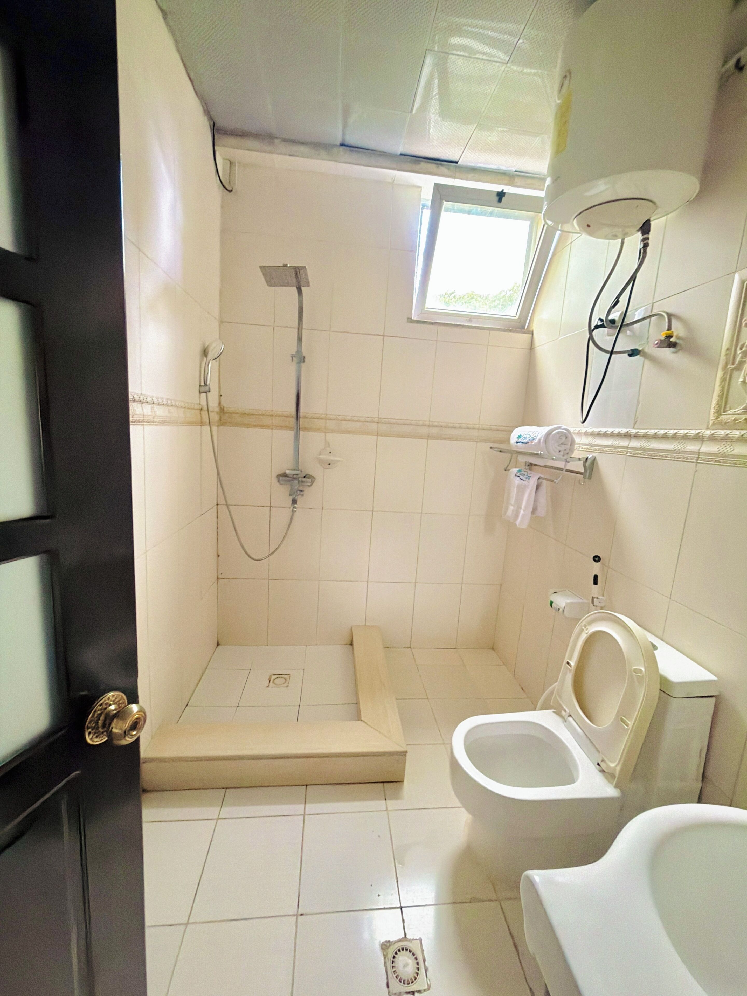 Un baño con ducha, inodoro y ventana que proporciona luz natural.