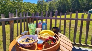 A breakfast tray with cereal, toast, fruit, and drinks on a wooden table with a view of a forested mountain. - NOOSA ECO RETREAT (Pomona)